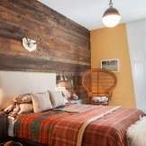 Merancang bilik tidur dengan hiasan dinding tunggal di dalam kayu