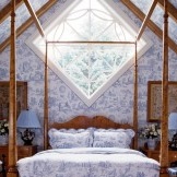 Textilien und Kissen auf dem Bett wiederholen das Tapetenmuster an der Wand