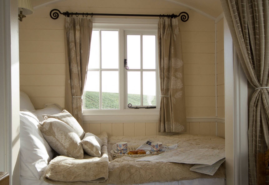 Ein kleines Bett am Fenster hinter dem Vorhang