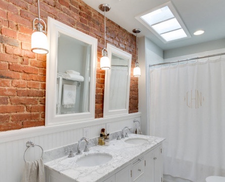 Dua cermin putih pada dinding bata di bilik mandi